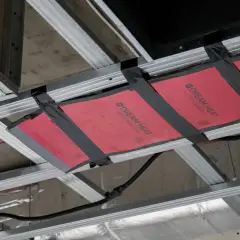 Instalacja grzejnika na podczerwień w suficie podwieszanym. Wady montażu widoczne na taśmie mocującej.