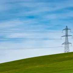Słupy energetyczne na zielonym wzgórzu, symbolizujące zmianę dostawcy prądu i nowoczesność.