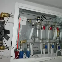 Instalacja ogrzewania podłogowego w bloku: rozdzielacz z zaworami i pompką, zasilanie i powrót z pieca.