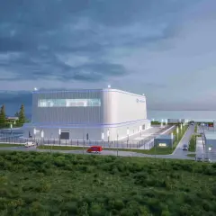 Nowoczesny reaktor jądrowy Hitachi, otoczony zielenią i infrastrukturą, z widokiem na morze.