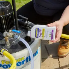 Osoba dodaje środek do czyszczenia instalacji co do urządzenia Fernox Powerflow.