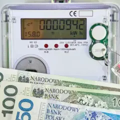 Licznik energii elektrycznej z banknotami 100 zł. Zastanawiasz się, ile kosztuje 1 kWh Enea?