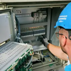Elektryk pracuje przy panelu sterowania, przygotowując oświadczenie o gotowości instalacji przyłączanej.