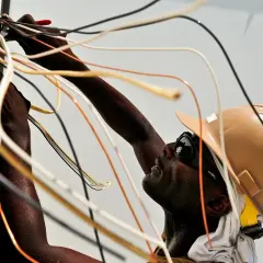 Elektryk w kasku i okularach pracuje przy instalacji elektrycznej, łącząc przewody. To dobry przykład, jak zostać elektrykiem.