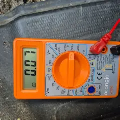 Pomarańczowy multimetr pokazuje 0.07A, co jest pomocne, gdy chcesz sprawdzić pobór prądu w samochodzie.