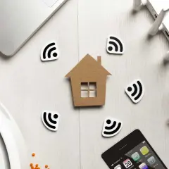 Dom z symbolami Wi-Fi, laptop, router, telefon i robot sprzątający. Wszystko to tworzy obraz inteligentnego domu, gdzie technologia i komfort idą w parze, a zasięg sieci jest wszędzie, minimalizując potencjalne **emf**.