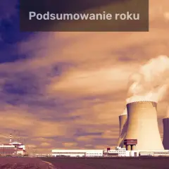 Podsumowanie roku w fizyce jądrowej: elektrownia z chłodniami kominowymi i budynkami przemysłowymi na tle dramatycznego nieba.