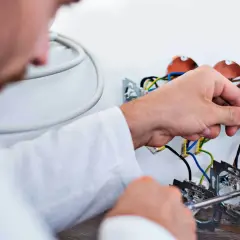 Elektryk podłącza przewody. Szacowany koszt wymiany instalacji elektrycznej w mieszkaniu 50m2.