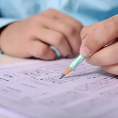 Ręka z ołówkiem zaznacza odpowiedzi na arkuszu egzaminacyjnym. To przygotowanie do egzaminu SEP, gdzie pytania i odpowiedzi są kluczowe.