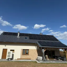 Dom z panelami fotowoltaicznymi na dachu. Zastanawiasz się, ile kosztuje fotowoltaika? To inwestycja w przyszłość i oszczędności.