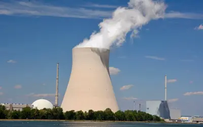 Chłodnia kominowa i budynki elektrowni atomowych w Niemczech na tle błękitnego nieba.