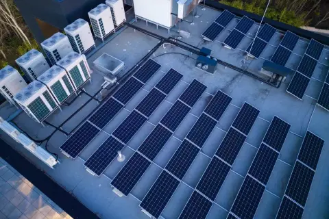 Panele słoneczne i jednostki klimatyzacyjne na dachu. Systemy te, choć różne, współpracują, minimalizując reaktancję i optymalizując zużycie energii.