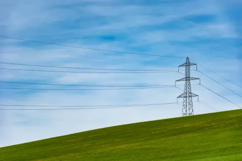 Słupy energetyczne na zielonym wzgórzu, symbolizujące zmianę dostawcy prądu i nowoczesność.