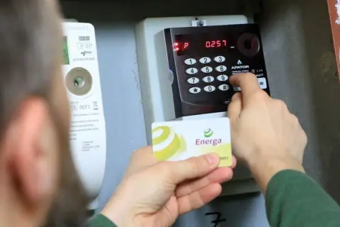Doładowanie licznika PGE w weekend. Karta Energa w dłoni, wprowadzanie kodu na klawiaturze licznika.