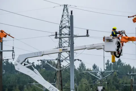 Pracownicy PGE w koszach podnośników naprawiają linię energetyczną, usuwając skutki awarii prądu.