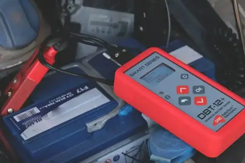 Tester akumulatorów podłączony do baterii samochodowej. Pokazuje napięcie 14.25V. To prosty sposób, jak sprawdzić akumulator.