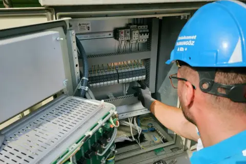 Elektryk pracuje przy panelu sterowania, przygotowując oświadczenie o gotowości instalacji przyłączanej.