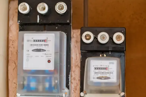 Dwa liczniki energii elektrycznej, jeden z czerwonym wskaźnikiem awarii. Uważaj na oszustów przy wymianie licznika Tauron.