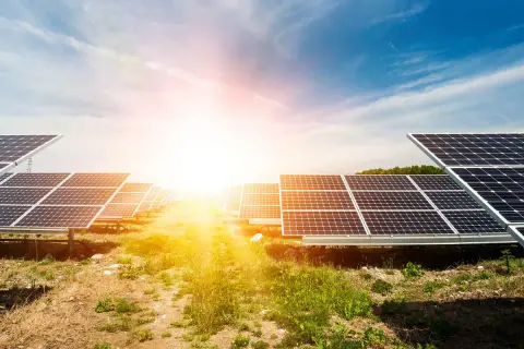 Rzędy paneli fotowoltaicznych na tle słonecznego nieba. Ta farma fotowoltaiczna zbiera energię ze słońca.