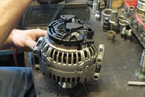 Warsztat samochodowy, gdzie mechanik sprawdza alternator. Dowiedz się, ile kosztuje regeneracja alternatora i jakie części są potrzebne.