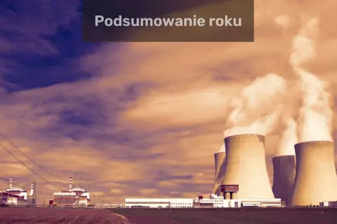 Podsumowanie roku w fizyce jądrowej: elektrownia z chłodniami kominowymi i budynkami przemysłowymi na tle dramatycznego nieba.