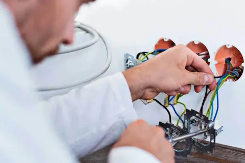 Elektryk podłącza przewody. Szacowany koszt wymiany instalacji elektrycznej w mieszkaniu 50m2.