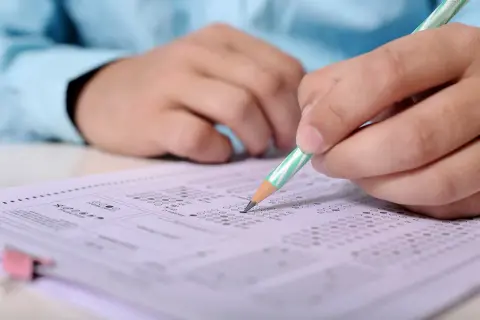 Ręka z ołówkiem zaznacza odpowiedzi na arkuszu egzaminacyjnym. To przygotowanie do egzaminu SEP, gdzie pytania i odpowiedzi są kluczowe.