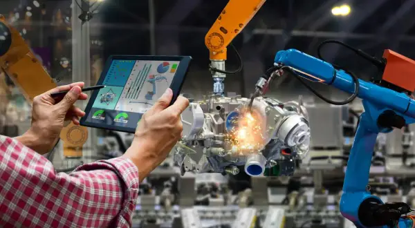 Operator kontroluje pracę robotów spawalniczych na tablecie, optymalizując procesy dla większych automatyk zarobki.