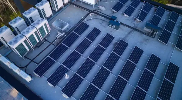 Panele słoneczne i jednostki klimatyzacyjne na dachu. Systemy te, choć różne, współpracują, minimalizując reaktancję i optymalizując zużycie energii.