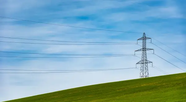 Słupy energetyczne na zielonym wzgórzu, symbolizujące zmianę dostawcy prądu i nowoczesność.