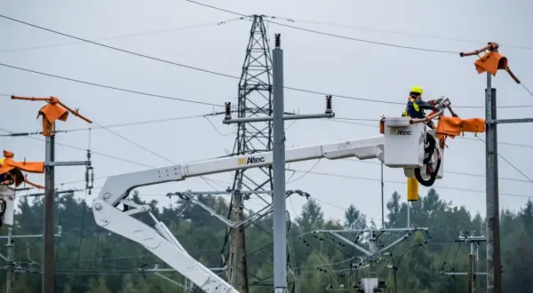 Pracownicy PGE w koszach podnośników naprawiają linię energetyczną, usuwając skutki awarii prądu.