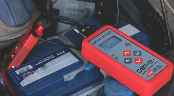 Tester akumulatorów podłączony do baterii samochodowej. Pokazuje napięcie 14.25V. To prosty sposób, jak sprawdzić akumulator.