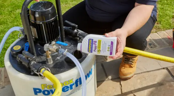 Osoba dodaje środek do czyszczenia instalacji co do urządzenia Fernox Powerflow.