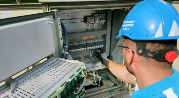 Elektryk pracuje przy panelu sterowania, przygotowując oświadczenie o gotowości instalacji przyłączanej.