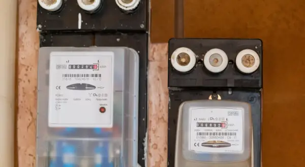 Dwa liczniki energii elektrycznej, jeden z czerwonym wskaźnikiem awarii. Uważaj na oszustów przy wymianie licznika Tauron.