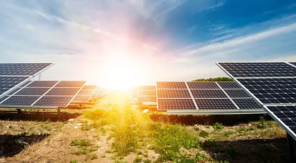 Rzędy paneli fotowoltaicznych na tle słonecznego nieba. Ta farma fotowoltaiczna zbiera energię ze słońca.