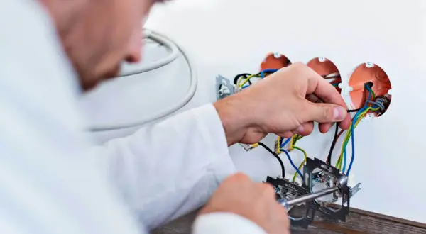 Elektryk podłącza przewody. Szacowany koszt wymiany instalacji elektrycznej w mieszkaniu 50m2.
