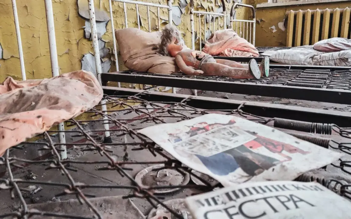 Opuszczona sala szpitalna, zniszczona lalka na łóżku, zardzewiałe sprężyny i gazeta z napisem "МЕДИЦИНСКАЯ СЕСТРА" - przejmujące świadectwo czarnobylskich skutków.