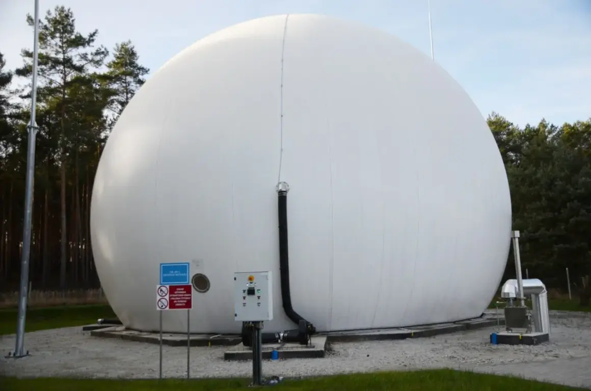 Ogromny, biały balon magazynujący biometan, otoczony drzewami. Obok znajduje się panel sterowania i rury.