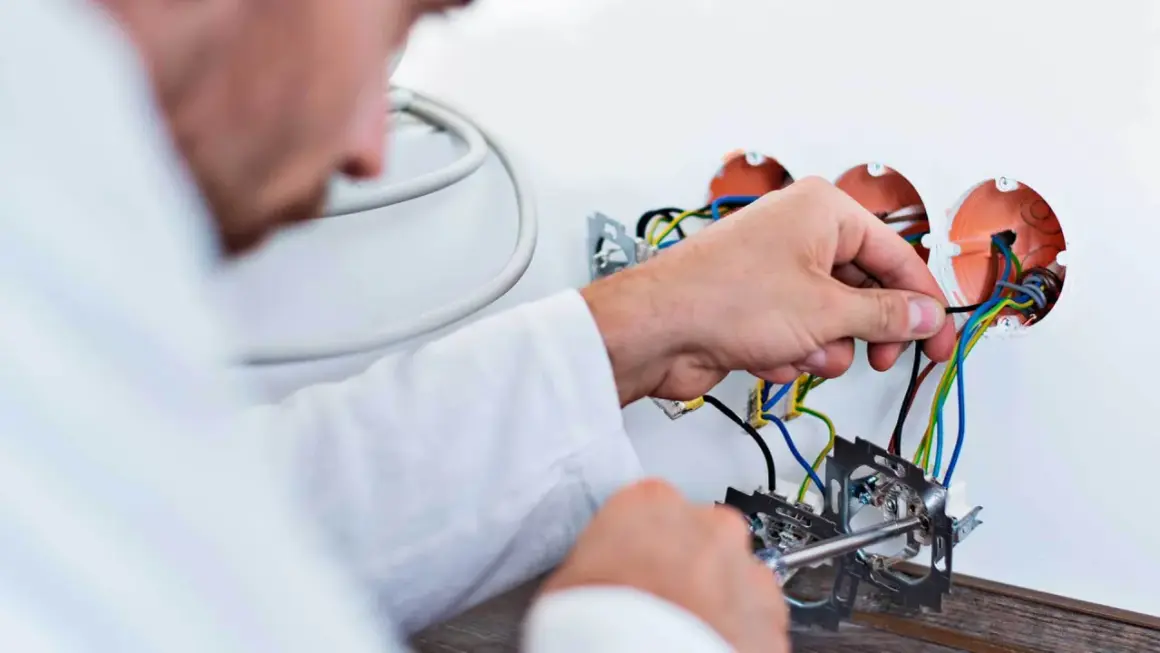 Elektryk podłącza przewody. Szacowany koszt wymiany instalacji elektrycznej w mieszkaniu 50m2.