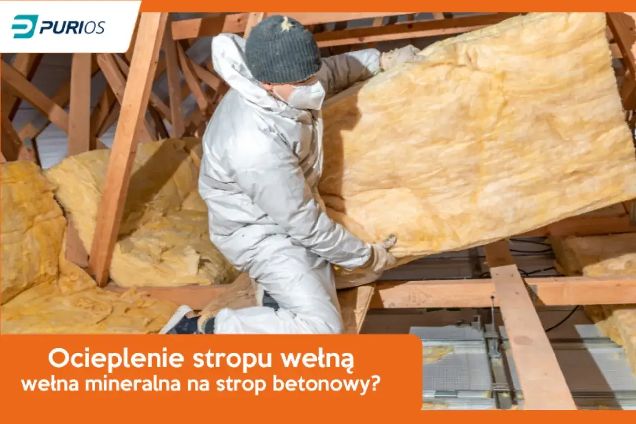 Ocieplenie stropu drewnianego wełną mineralną. Pracownik w kombinezonie montuje izolację w poddaszu.