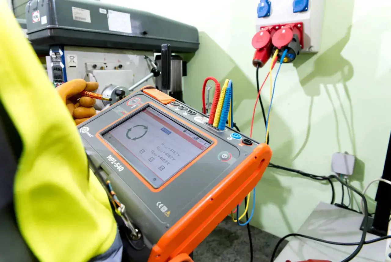 Elektryk dokonuje odbioru instalacji elektrycznej za pomocą miernika MPI-540. Urządzenie pokazuje wyniki pomiarów napięcia.
