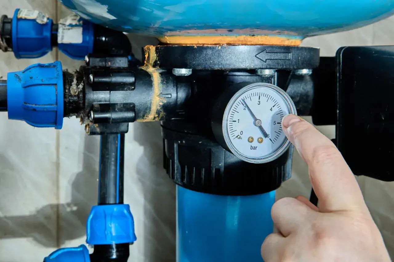 Palec wskazuje manometr hydroforu, pokazując ciśnienie. Proces odpowietrzania hydroforu wymaga kontroli ciśnienia.