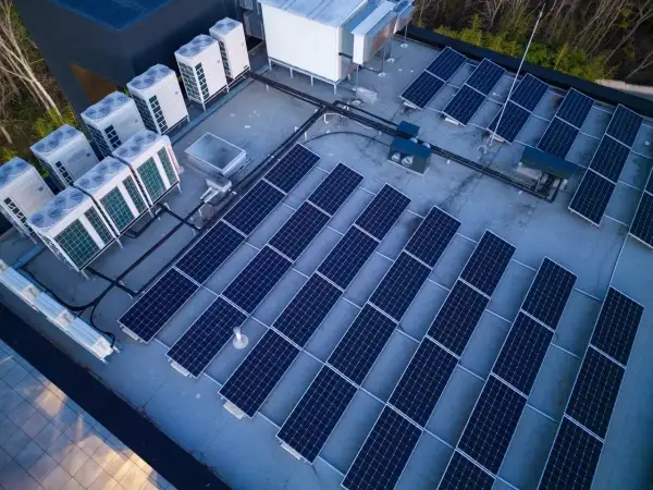 Panele słoneczne i jednostki klimatyzacyjne na dachu. Systemy te, choć różne, współpracują, minimalizując reaktancję i optymalizując zużycie energii.