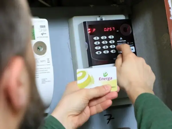 Doładowanie licznika PGE w weekend. Karta Energa w dłoni, wprowadzanie kodu na klawiaturze licznika.