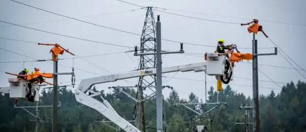 Pracownicy PGE w koszach podnośników naprawiają linię energetyczną, usuwając skutki awarii prądu.