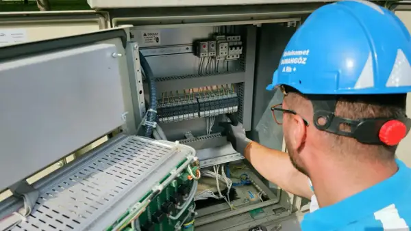 Elektryk pracuje przy panelu sterowania, przygotowując oświadczenie o gotowości instalacji przyłączanej.