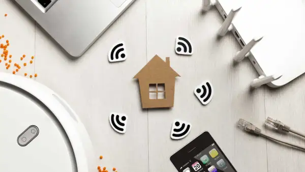 Dom z symbolami Wi-Fi, laptop, router, telefon i robot sprzątający. Wszystko to tworzy obraz inteligentnego domu, gdzie technologia i komfort idą w parze, a zasięg sieci jest wszędzie, minimalizując potencjalne **emf**.