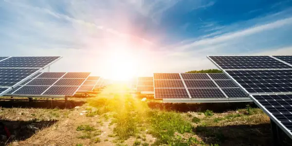 Rzędy paneli fotowoltaicznych na tle słonecznego nieba. Ta farma fotowoltaiczna zbiera energię ze słońca.