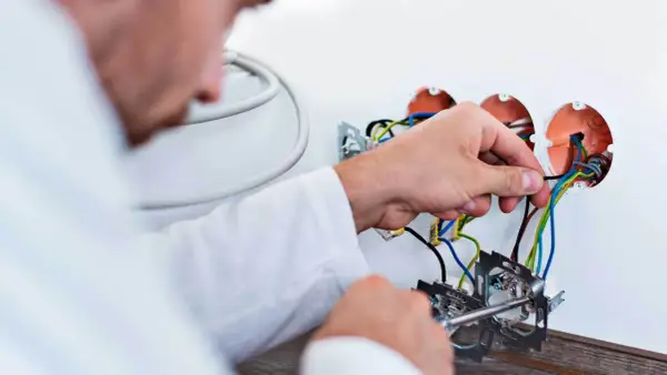 Elektryk podłącza przewody. Szacowany koszt wymiany instalacji elektrycznej w mieszkaniu 50m2.